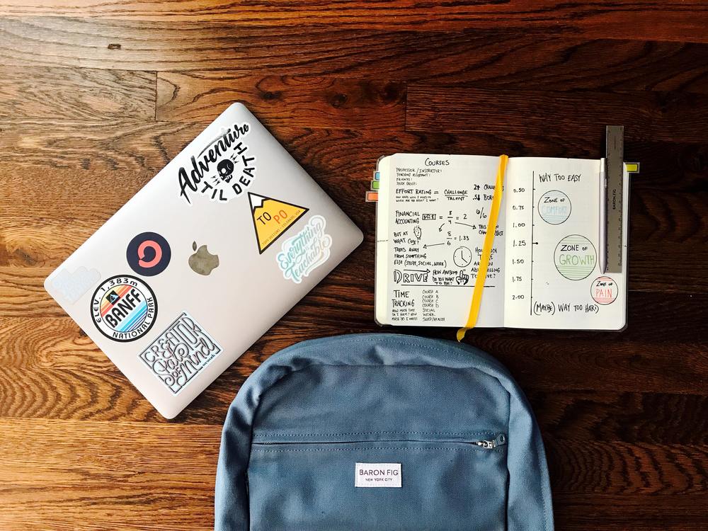 laptop, notebook, and backpack on a desk